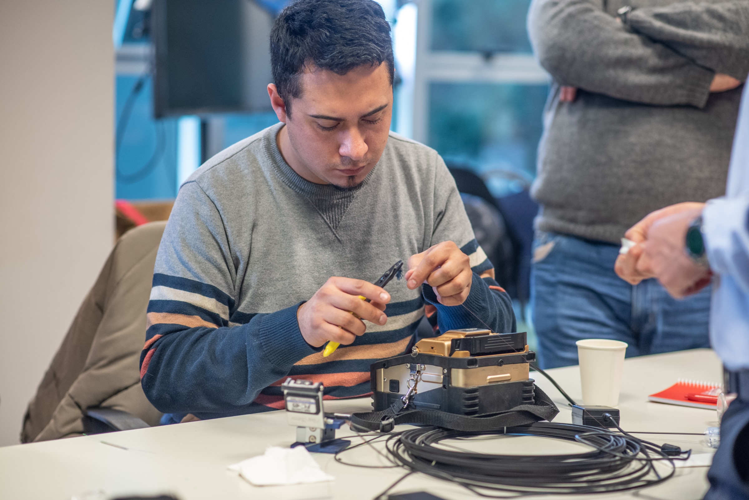 Alumno de COMFI realizando una práctica con una fusionadora de fibra óptica